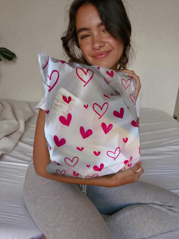 Mujer en su cama abrazando la bolsita de corazones cerrada